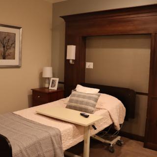 A cozy hospital room featuring a bed, bedside tables with lamps, and decorative elements creating a warm atmosphere.