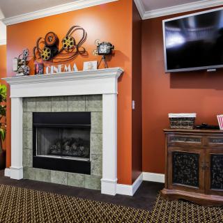A cozy living room with an orange accent wall, featuring a fireplace and a mounted TV.