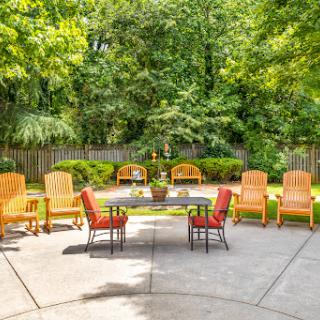 A serene outdoor patio area featuring comfortable seating surrounded by lush greenery.