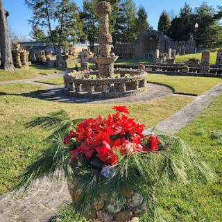 A vibrant garden featuring a beautiful fountain surrounded by blooming red flowers.