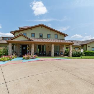 A large residential building with a spacious driveway and well-maintained landscaping under a partly cloudy sky.