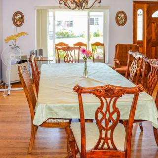A bright dining room with a long wooden table surrounded by matching chairs and a floral centerpiece.