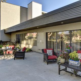 A modern patio with comfortable seating and vibrant plants under a sunny sky.