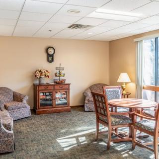 A cozy living room with comfortable seating, a wooden table and chairs, and decorative elements like a clock and lamp.