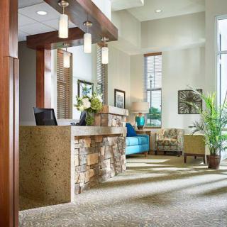 A bright and modern lobby featuring a reception area, comfortable seating, and decorative plants.