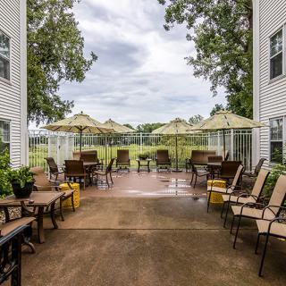 A cozy outdoor patio area with chairs, tables, and umbrellas between two buildings.