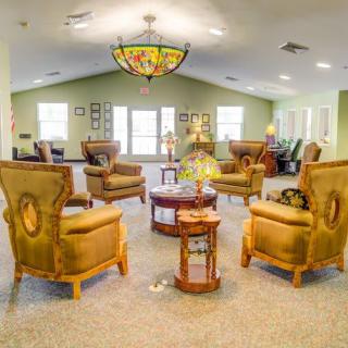 A warmly decorated living room with elegant chairs arranged around a central coffee table.