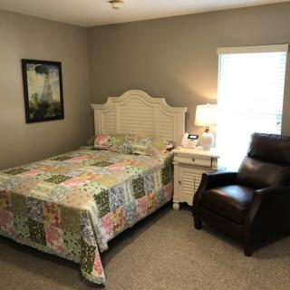 A cozy bedroom with a quilt-covered bed and leather armchair.