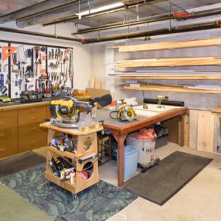 A well-organized woodworking workshop with tools displayed on the wall and a central workbench.