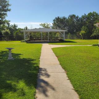 A serene view of a park featuring a charming gazebo and a well-maintained pathway surrounded by lush green grass.