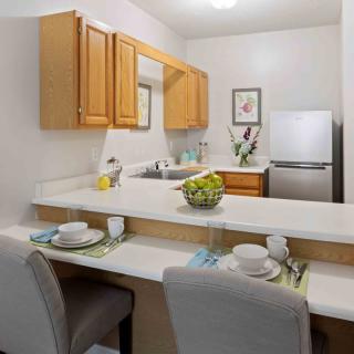 A modern kitchen with a breakfast bar, featuring wooden cabinets and sleek appliances.