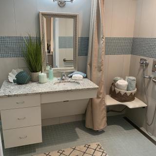 A neatly organized bathroom with a large mirror, countertop decor, and a shower area.