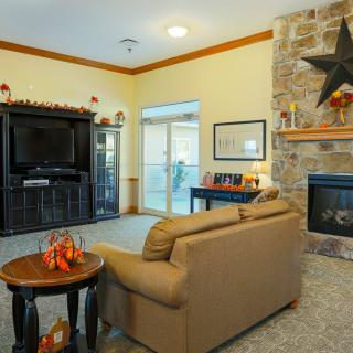 A cozy living room featuring a couch, stone fireplace, television, and decorative elements.
