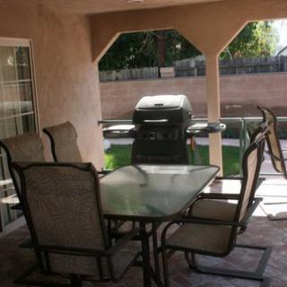 A cozy outdoor patio setup with a table, chairs, and a grill in the backyard.