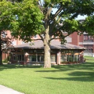 A brick building surrounded by lush green grass and trees on a sunny day.