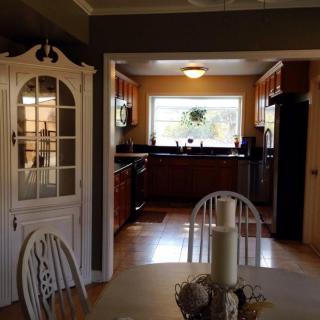 A cozy view of an open kitchen and dining area with wooden cabinets and a dining table.