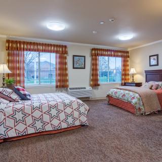 A cozy hotel room with two double beds, warm lighting, and patterned curtains.