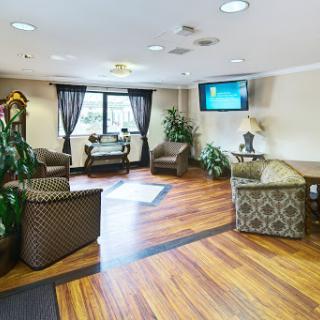 A cozy lobby area featuring comfortable seating, greenery, and a television.