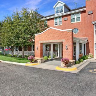 A welcoming entrance to a hotel featuring red brick architecture and landscaped surroundings.