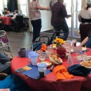 A group of people gathered around a dining table set for a social event indoors.