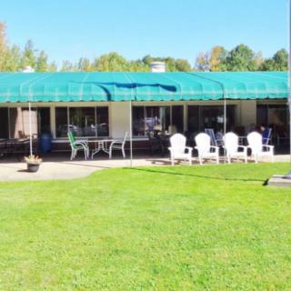 A sunny outdoor patio area with white chairs and a green canopy.