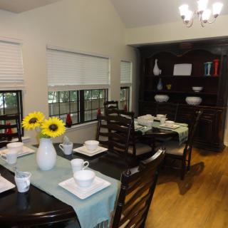 A well-lit dining room with a beautifully set table, featuring sunflowers as the centerpiece.