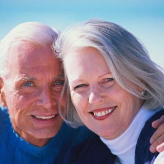 A joyful elderly couple smiling together, enjoying a day at the beach.