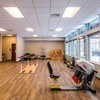 A well-lit and spacious gym area equipped with various exercise machines and open workout spaces.