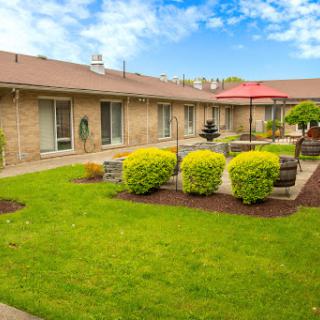 A serene courtyard featuring well-manicured lawns, comfortable outdoor seating, and a charming fountain.