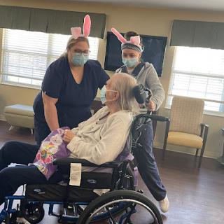 Caregivers celebrating with an elderly resident, spreading joy with playful bunny ears.
