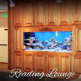 A cozy reading lounge featuring a built-in aquarium with vibrant marine life.