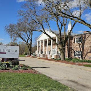 A picturesque view of a building with classical architecture, surrounded by trees and well-maintained landscaping.