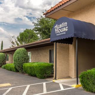 A hotel entrance featuring a blue awning and well-maintained landscaping.