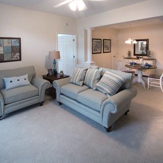 A cozy living room with a sofa and armchair, leading into a dining area.