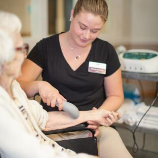 A caregiver providing therapy to an elderly woman.