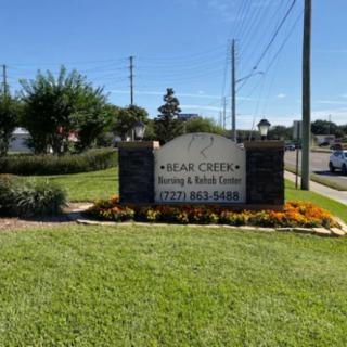 Sign for Oak Creek Nursing & Rehab Center surrounded by landscaped grass and flowers.