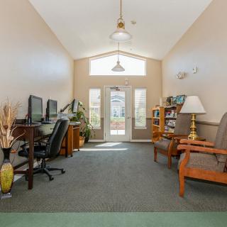 A cozy office space with computers, comfortable seating, and a bookshelf.