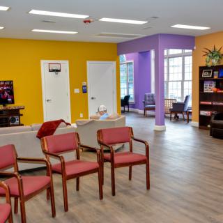 A colorful waiting room with chairs arranged neatly and bright walls.