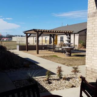 A serene backyard featuring a pergola and a well-maintained landscape under a clear blue sky.