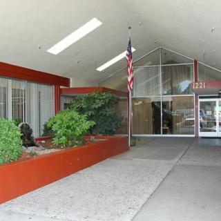 Main entrance of a modern building with a flagpole and landscaped area.