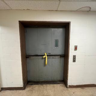A closed elevator door secured with yellow safety tape, indicating it's out of service.