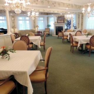 An elegant dining room with neatly arranged tables and chairs, illuminated by chandeliers.