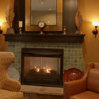 A cozy living room with a warm lit fireplace and comfortable seating.
