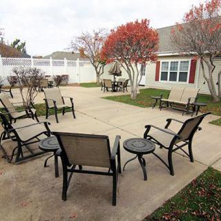 An outdoor patio area with chairs and tables surrounded by trees with autumn leaves.