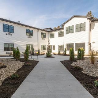 A modern building features a neatly landscaped courtyard with a central pathway.