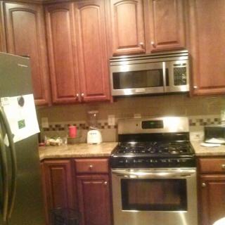 A modern kitchen with wooden cabinets, stainless steel appliances, and a tiled backsplash.