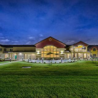 A well-lit building with surrounding lawns at night.