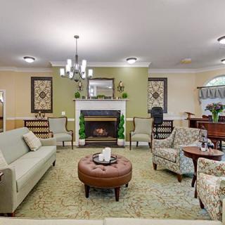 A cozy living room featuring a sofa, chairs, a central ottoman, and a fireplace.