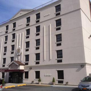 Exterior view of a multi-story hotel building with several windows and parked cars nearby.