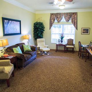 A cozy living room with a sofa, armchairs, and a large window.